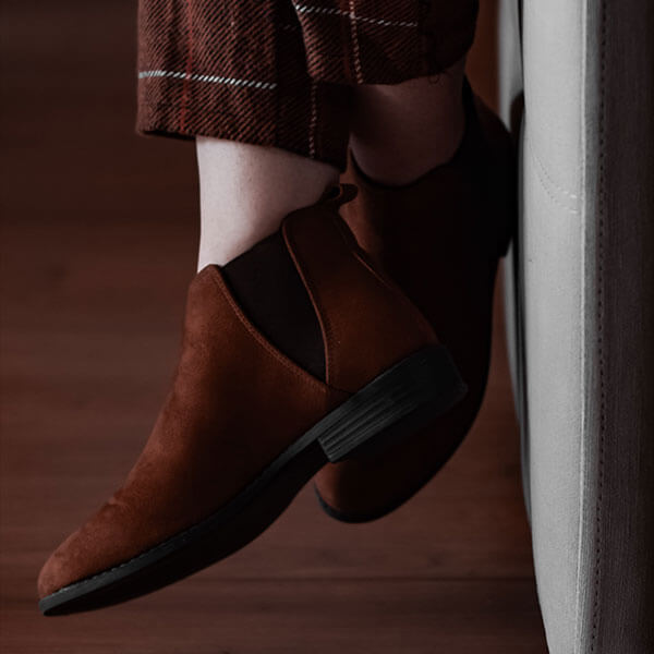 Close-up of stylish brown dress shoes for men, perfect for wedding attire, paired with plaid trousers, showcasing sophisticated footwear for bridal and groom looks.