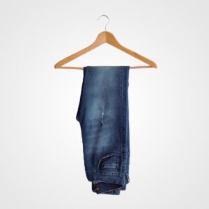 Pair of stylish blue denim jeans hanging on a wooden hanger, perfect for casual or semi-formal wear. Ideal for fashion-forward brides or bridal party accessories.