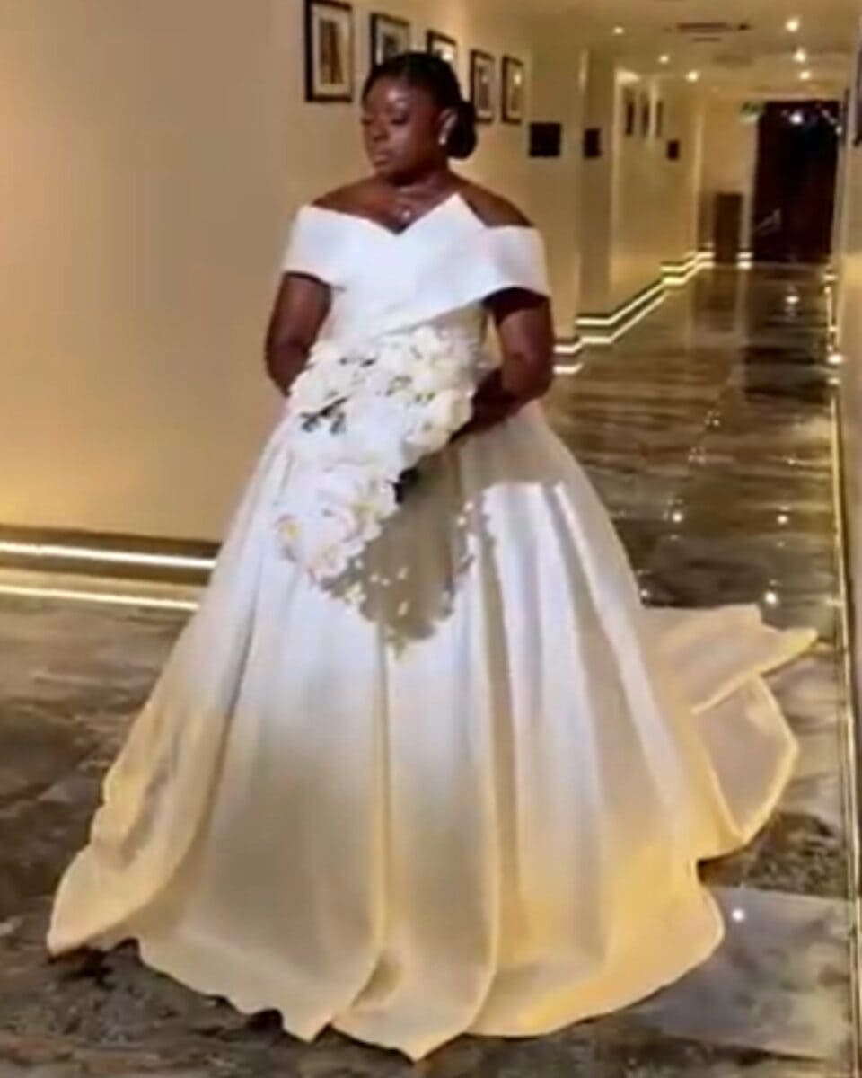 Elegant bridal dress featuring off-shoulder neckline and full skirt, perfect for a wedding day.
