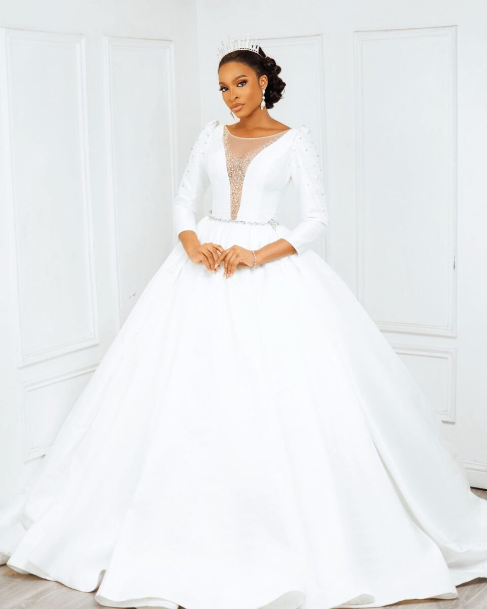 Elegant white bridal gown with lace details and a full skirt, perfect for a wedding at Yes I Do Bridal. Model showcases a classic, sophisticated wedding dress in a bright, stylish setting.